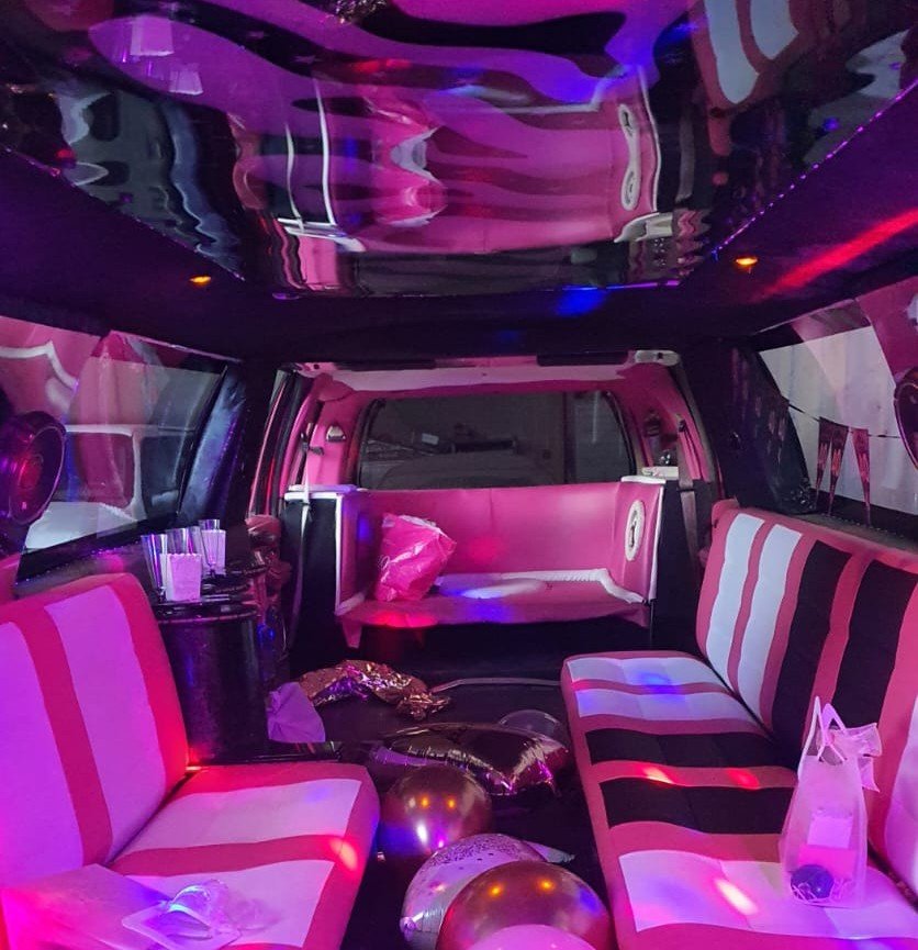 Interior de la limusina rosa La Barbie Navigator con luces LED azules, sofá cama, bar iluminado y ambiente de lujo para fiestas en Barcelona.