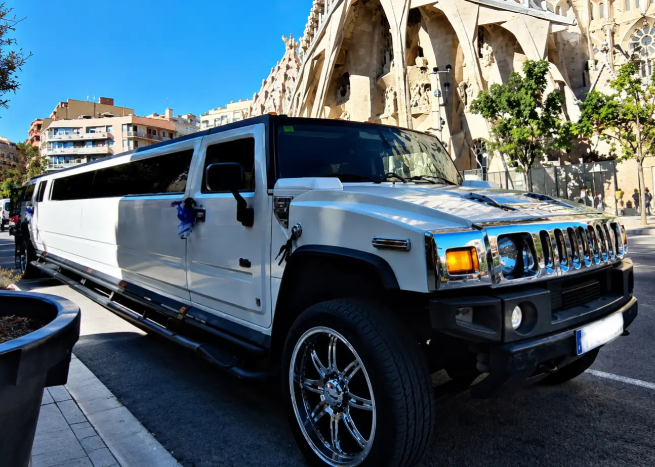 white Hummer limousine White Hummer stretch limousine in Barcelona, Spain, parked beside the Sagrada Família under a clear blue sky, featuring tinted windows and luxury finishes.